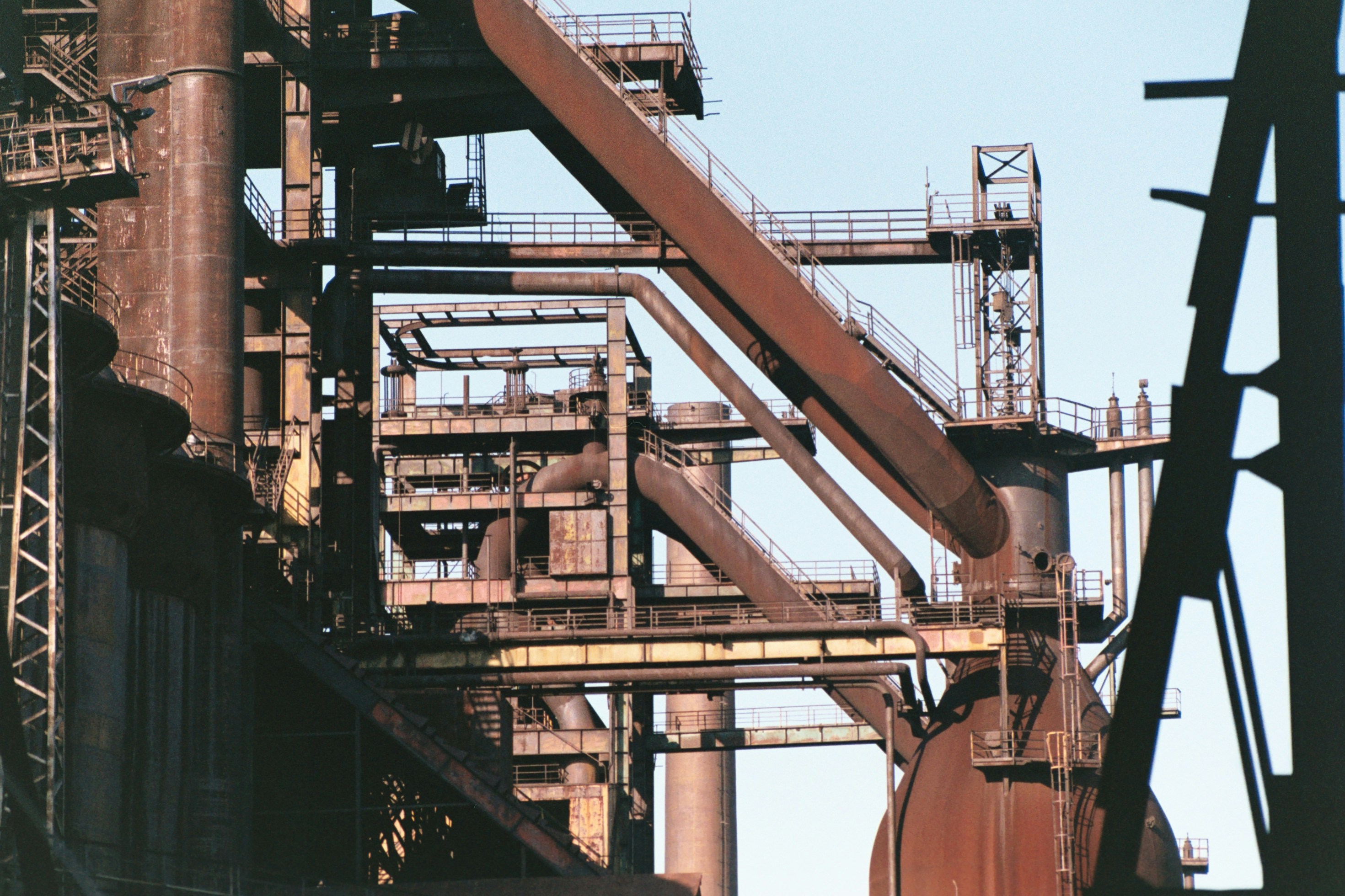 Industrial machinery and pipes against sky.